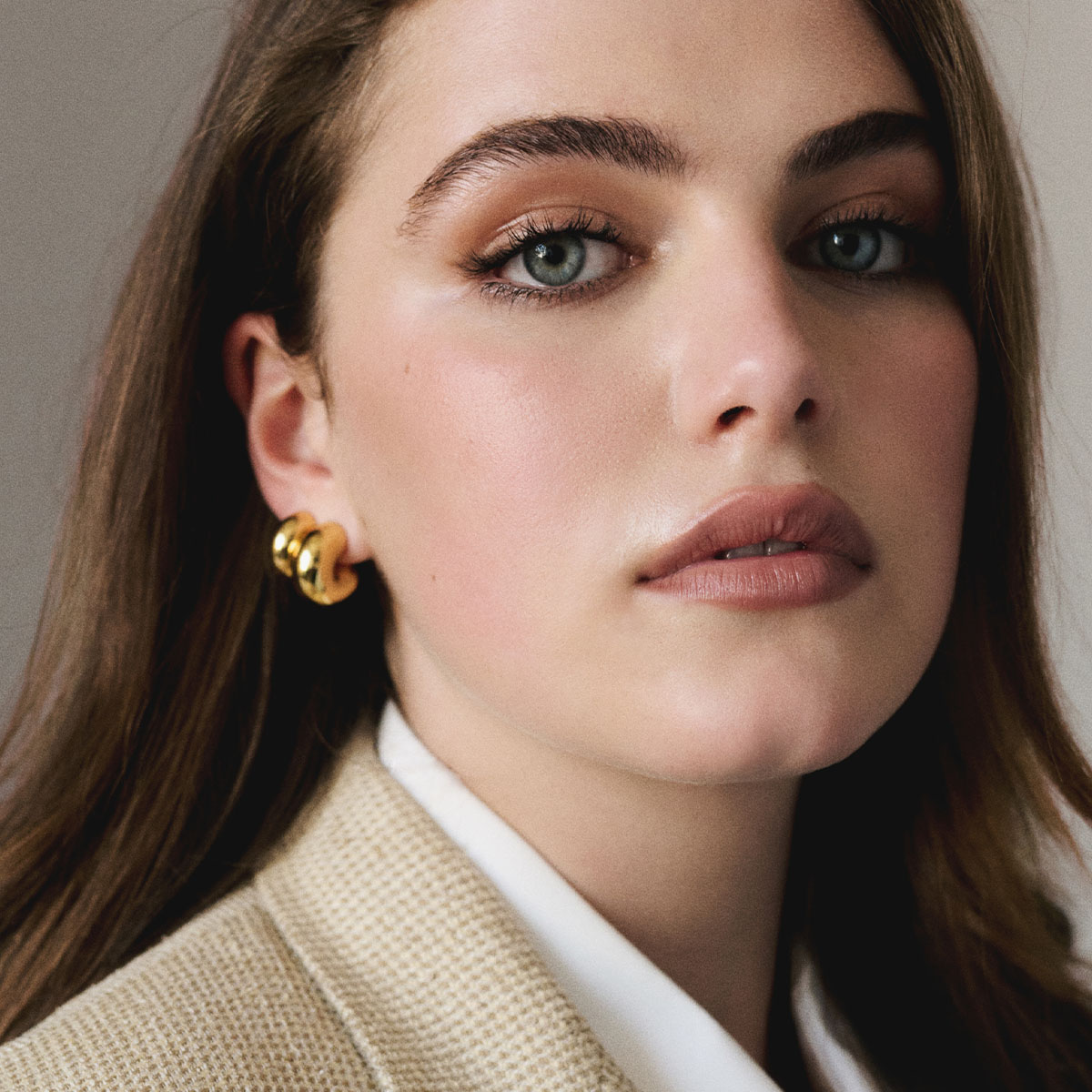 Portrait of actress Ella Bright wearing a beige blazer and gold hoop earrings. 