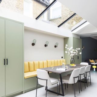 Green kitchen with yellow upholstered banquette seating and a glazed roof