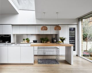 A white modern kitchen with a brushed stainless steel backsplash.