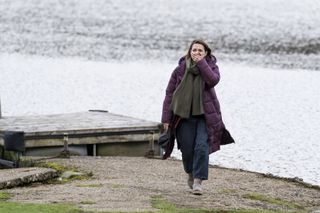 Dani (Kara Tointon) stands at the edge of a lake, holding a baseball cap in her hand, with her hand clamped over her mouth in horror and distress