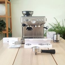 Sage The Barista Express BES875UK Espresso Coffee Machine with all of its accessories on a wooden table