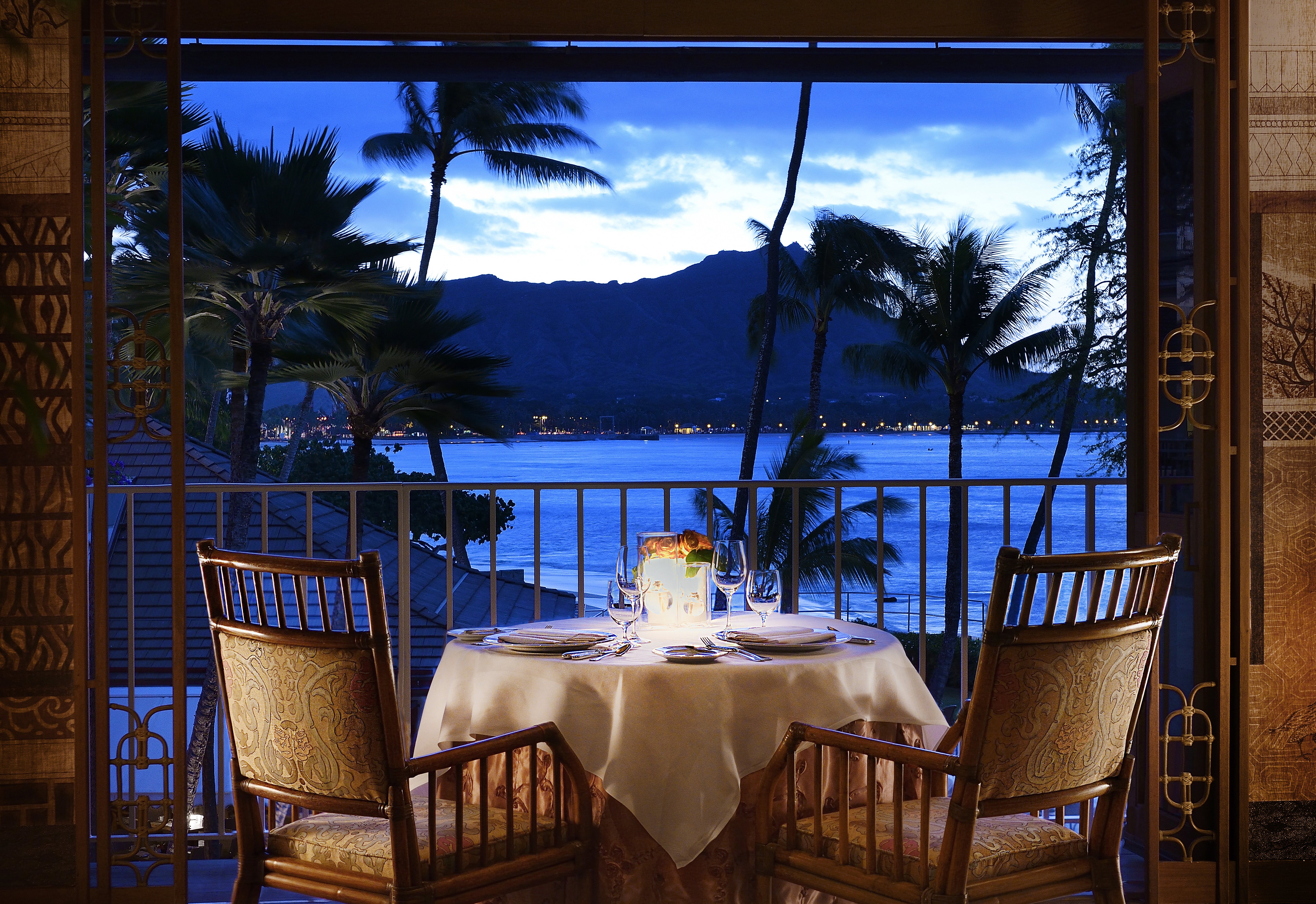 A table sitting in front of a balcony with an ocean view at the Halekulani hotel