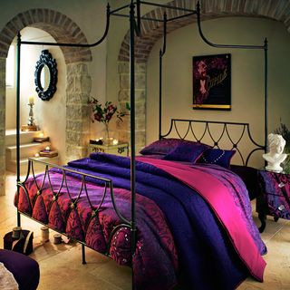 room with mirror on wall and purple colour bedlinen