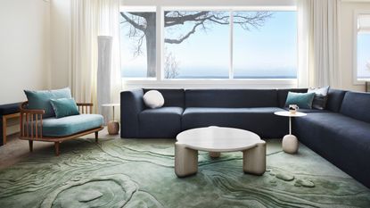 living room with seafoam textured rug with white coffee table, blue L-shaped sofa and teal armchair