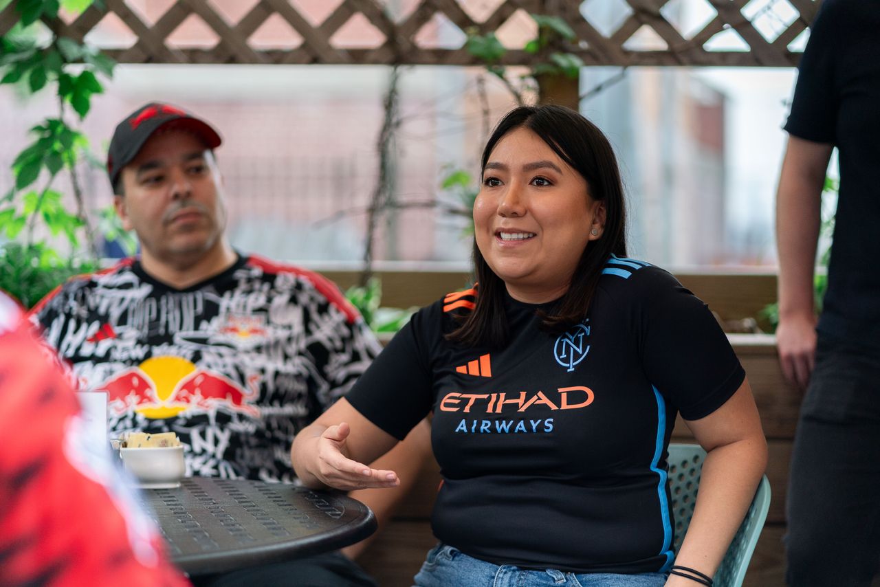 New York City FC fans Jenniffer Quezada smiles as she debates and talks with soccer fans outside a restaurant in Queens