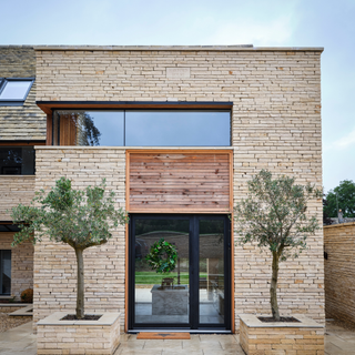 Modern brick home with two trees outside a glass front door