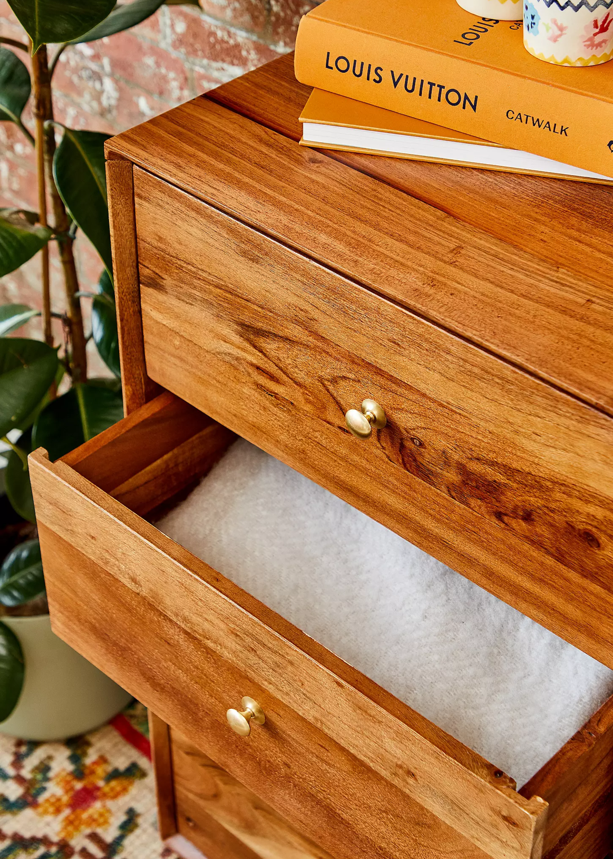 A wooden drawer with a folded fabric inside