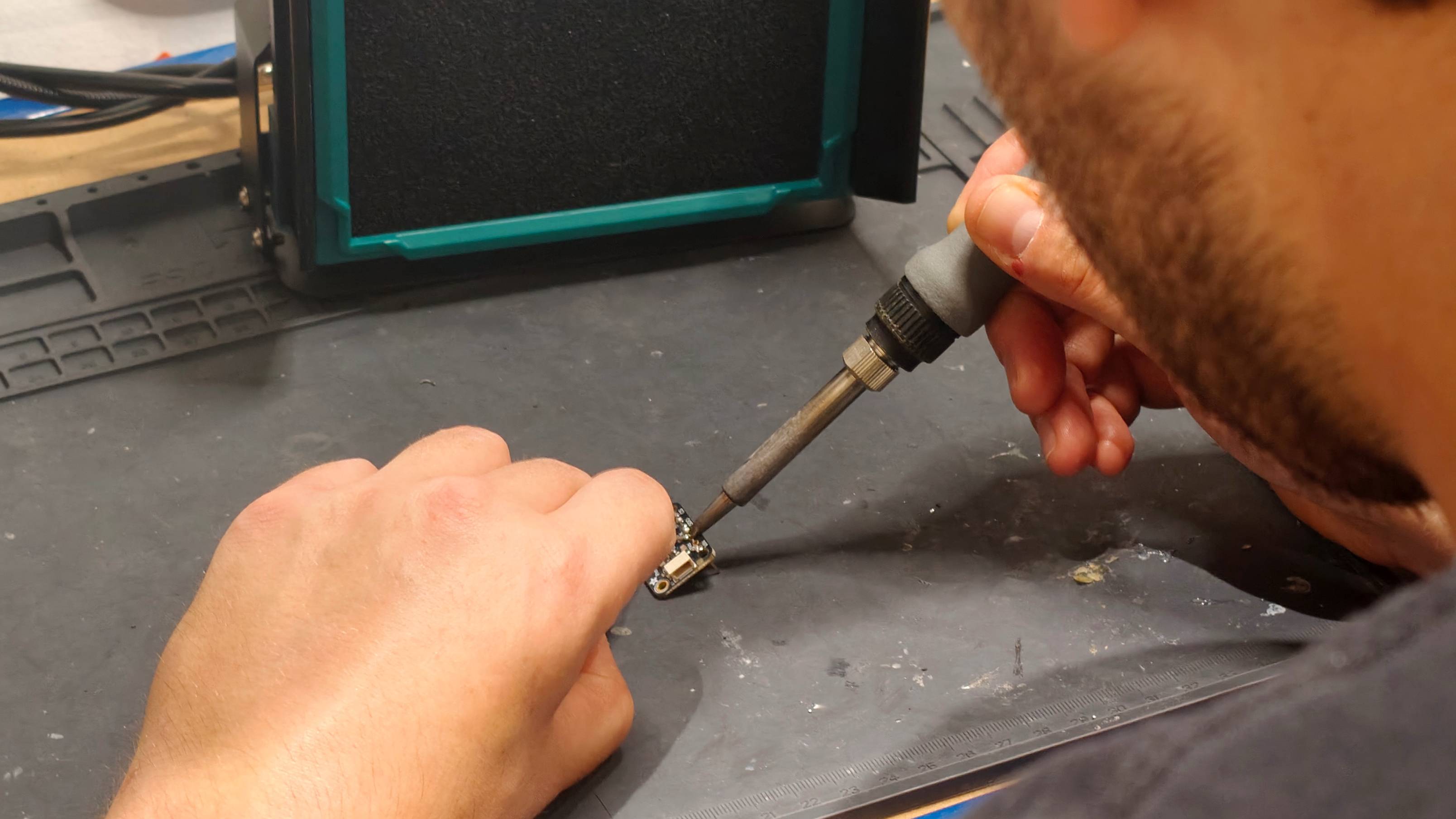 A picture over the shoulder of a man soldering some components.