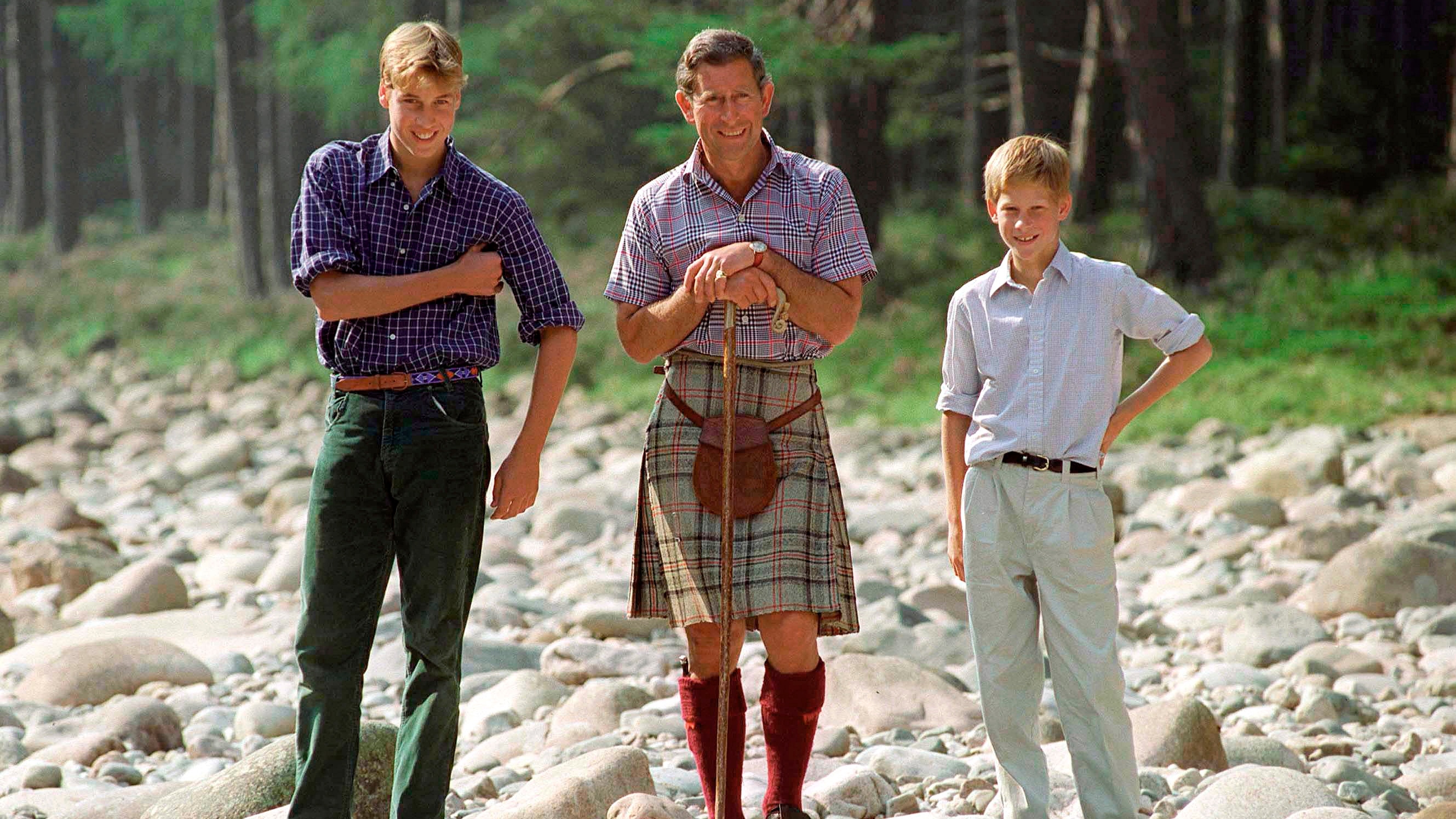 King Charles holds a walking stick, standing with Prince William and Prince Harry at Polvier, by the River Dee, Balmoral Castle Estate 1997