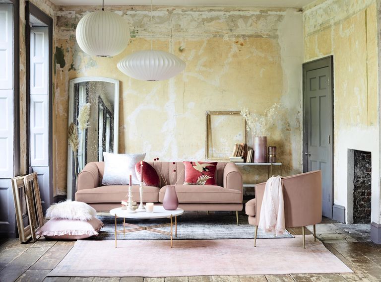 pink velvet sofas in a Parisian style apartment with a marble coffee table, mirrors, a rustic fireplace and a grey door