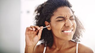 Woman using cotton swabs in her ears - something to be avoided to protect your hearing
