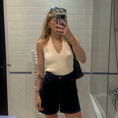 Eliza Huber wearing a cream-colored Zara halter top with dark-wash denim shorts and a brown Bottega Veneta Andiamo bag in a mirror selfie.
