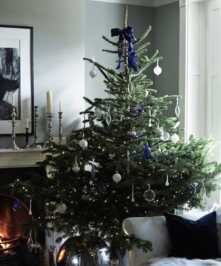 Christmas tree topper ideas with blue bow tied to the top of the tree