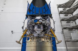 a space lander with protruding legs sits attached to its payload adapter in a white room. The Peregrine lunar lander, built by the Pittsburgh-based company Astrobotic, will launch toward the moon atop a United Launch Alliance Vulcan Centaur rocket on Jan. 8. 