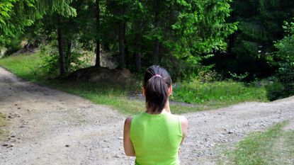 A woman stands at a fork in a path, contemplating which way to go.
