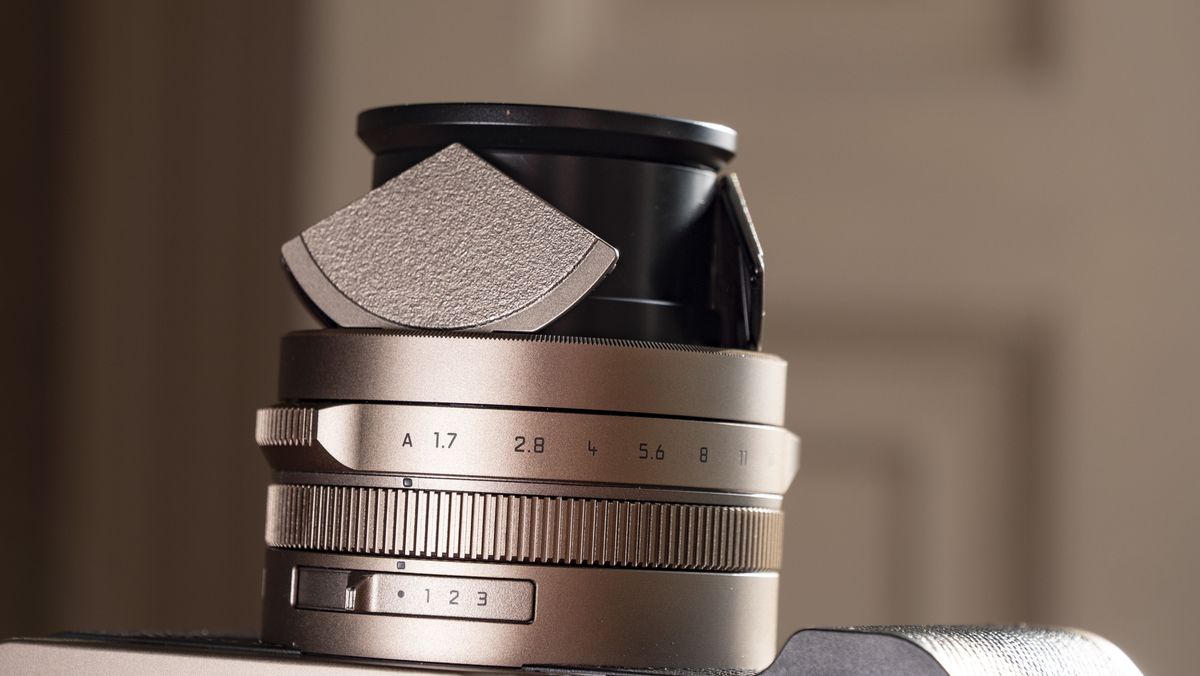 Close up of the lens of the Titanium Gold special edition of the Panasonic Lumix L10 compact camera, on an antique wooden table