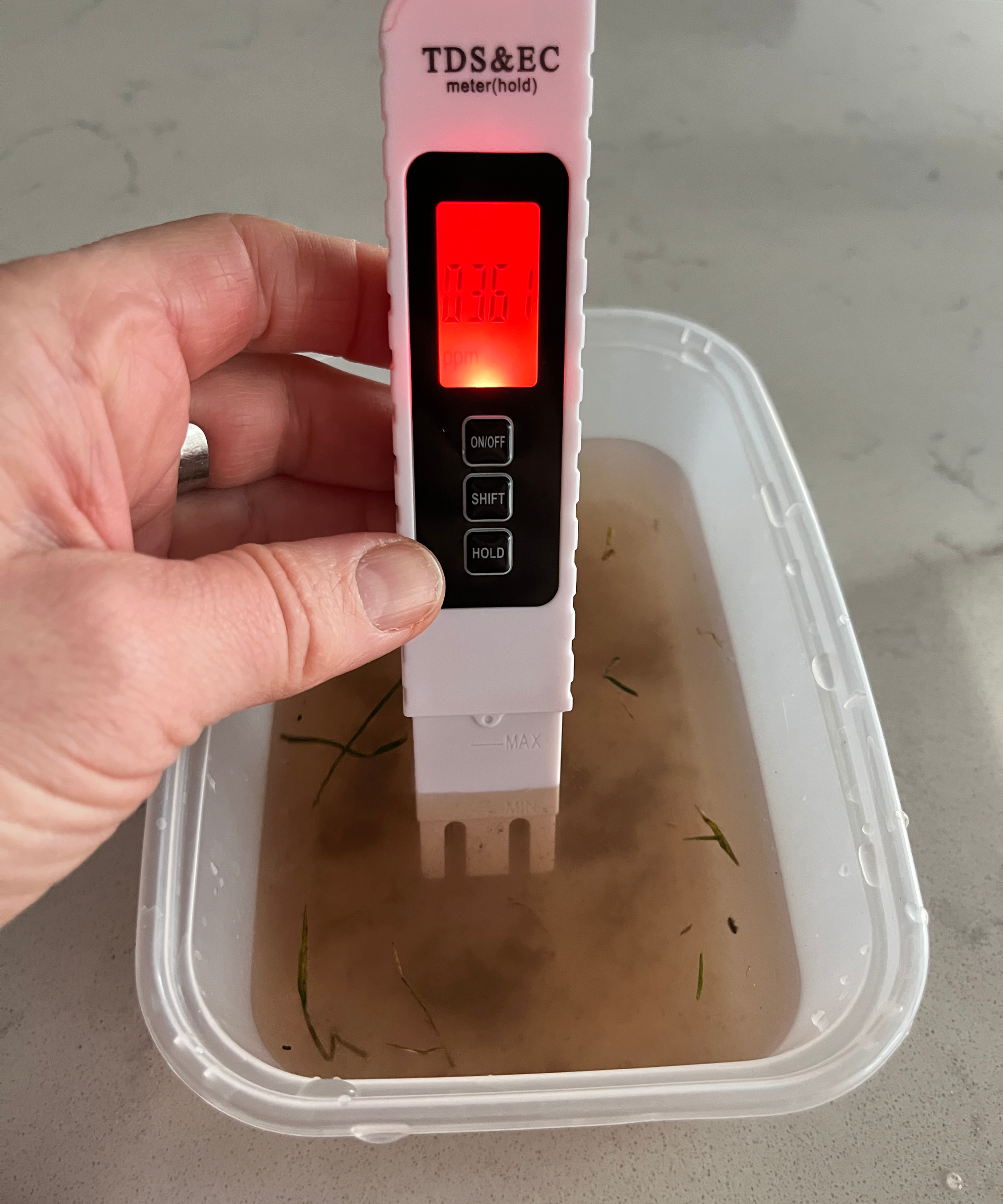 digital water tester placed in tub of dirty water