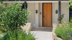 A front door with paved pathway lined with plants and greenery