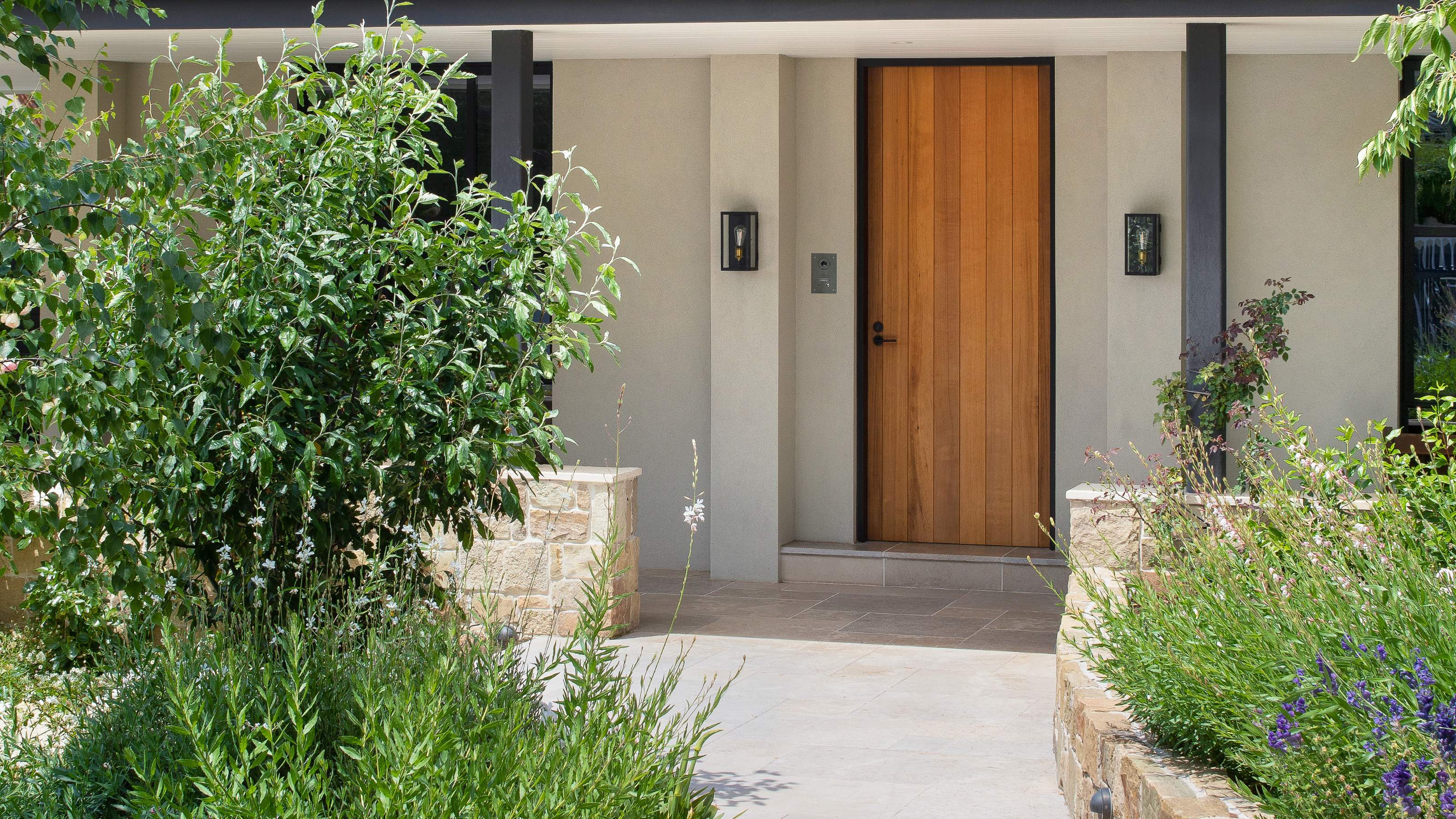 A front door with paved pathway lined with plants and greenery