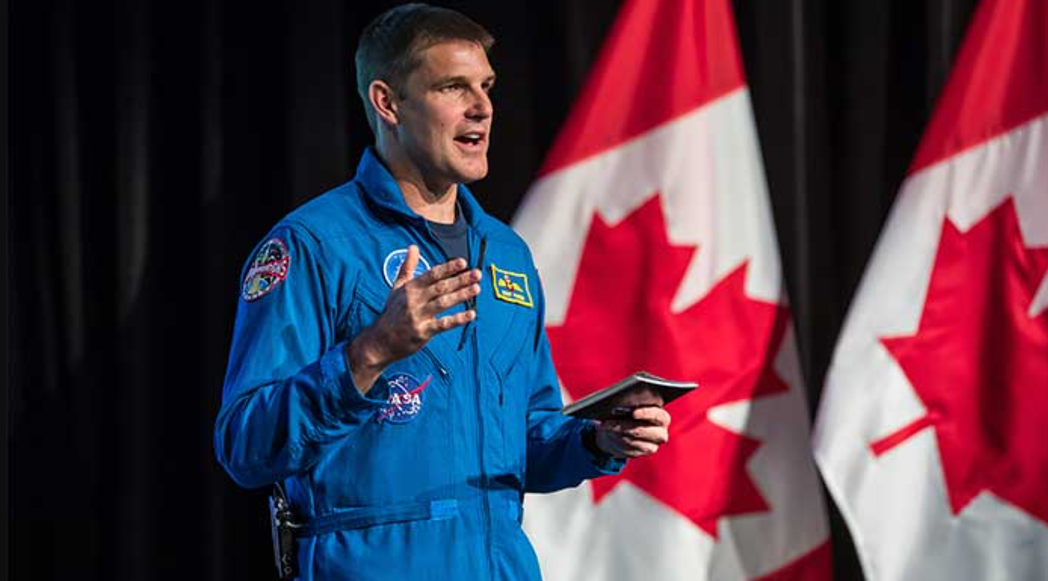 El astronauta de Artemis 2 Jeremy Hansen lleva la bandera canadiense durante su coronación