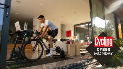 CYclist is seen on turbo trainer inside open plan house