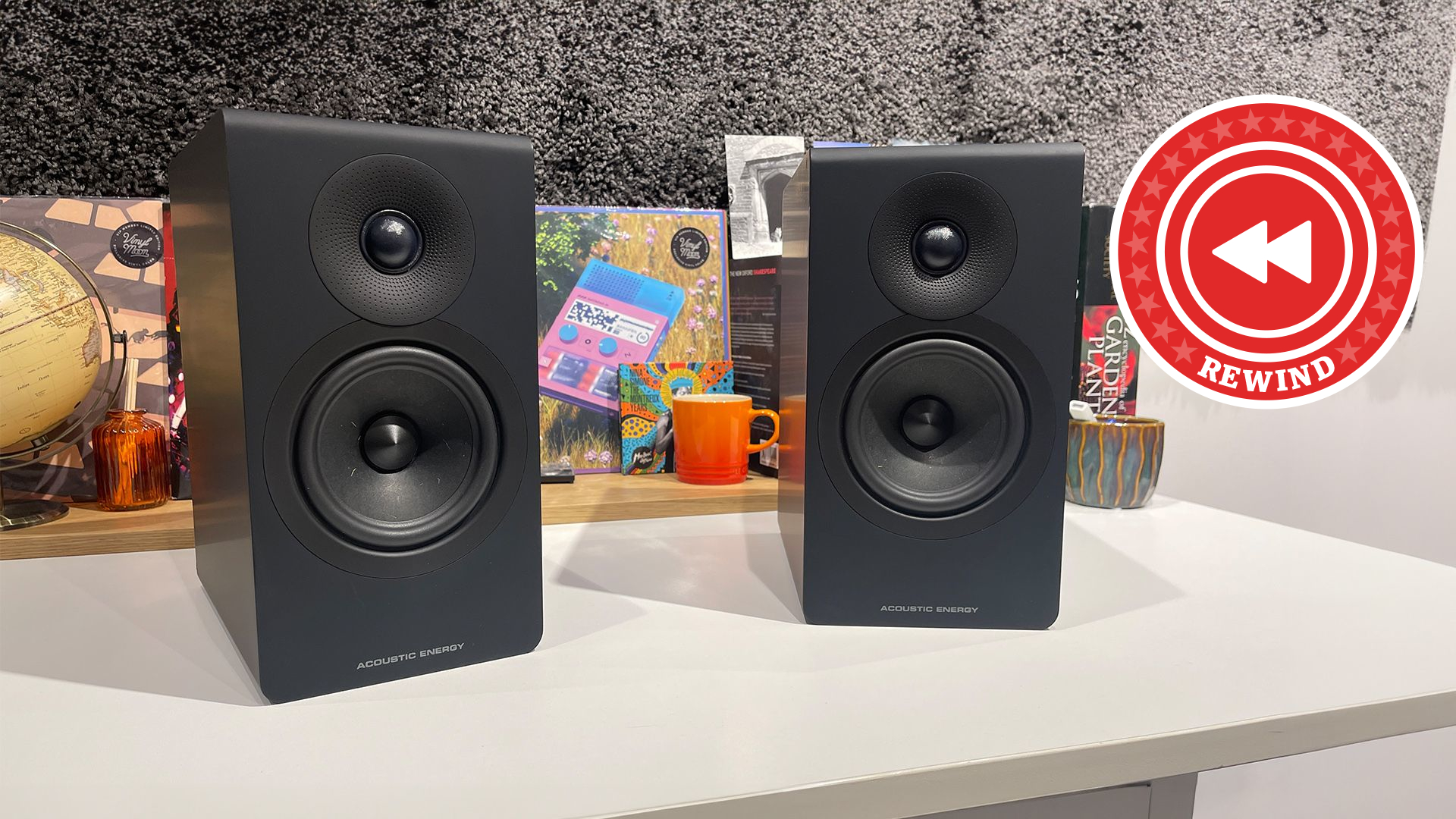 Acoustic Energy standmounts on table with Rewind logo