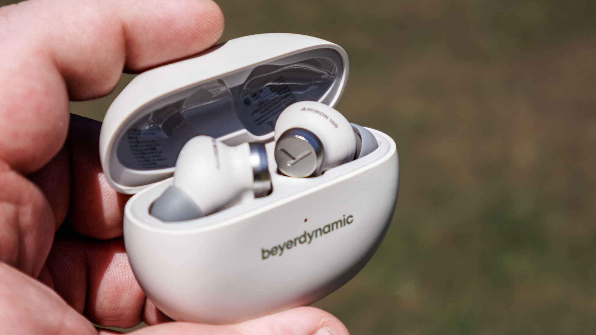 Beyerdynamic Amiron 100 case open with the earbuds inside, in a hand