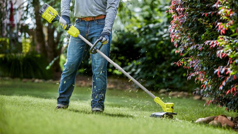 how to use a weed eater - man using a cordless Ryobi strimmer