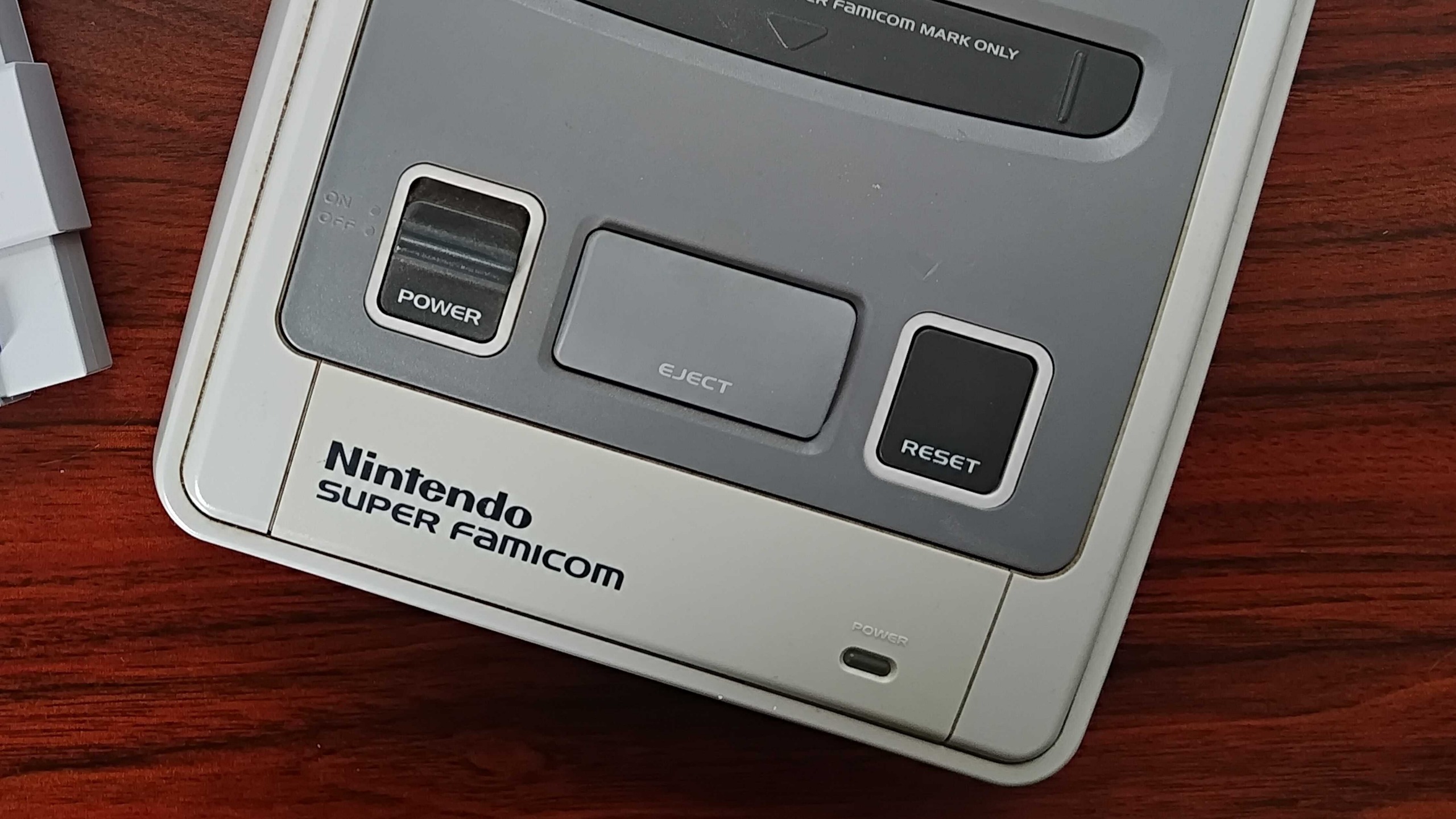 Close up of Super Famicom on woodgrain desk.
