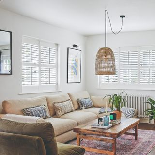 A small living room with a chaise beige sofa and an olive green chair to the side arranged around a rectangular wooden coffee table