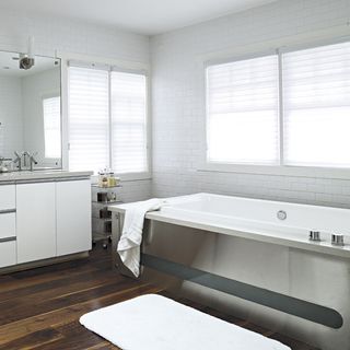 bathroom with white brick tile wall bathtub window wooden flooring