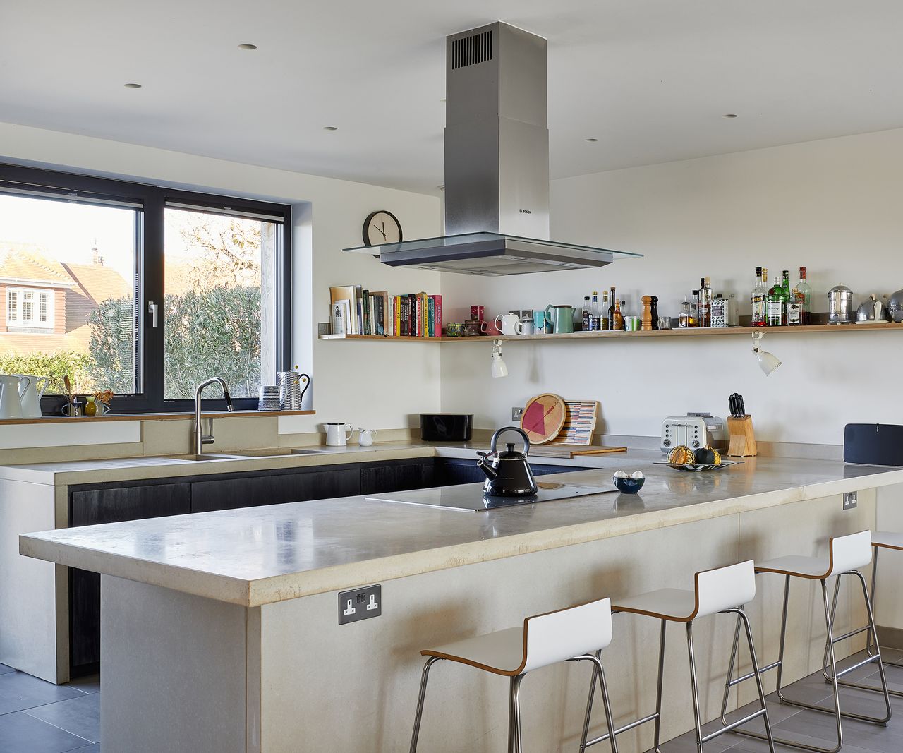 An open plan U shaped kitchen with bar stools and large extractor fan