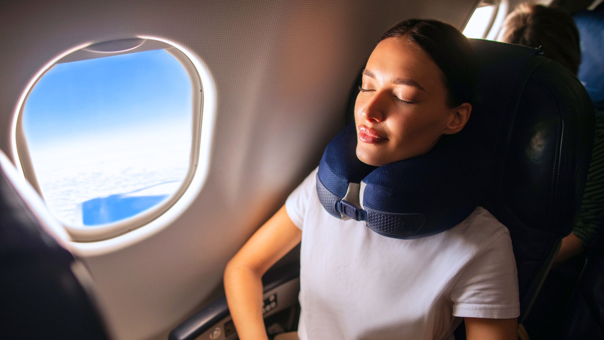 Woman with neck pillow and closed eyes resting during flight