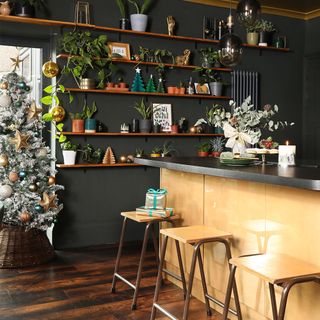 Black kitchen with gold island, bar stools, bi-fold windows and Christmas tree