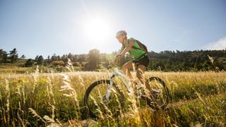 The benefits of exercising in the heat - woman cycling in the sun on a field