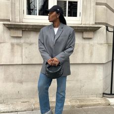 Influencer wears a grey blazer with blue jeans.