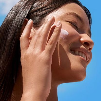 Applying sun cream to a cheek in the sun