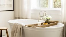 A white freestanding bath tub styles with a rattan bath caddy