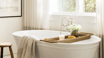 A white freestanding bath tub styles with a rattan bath caddy