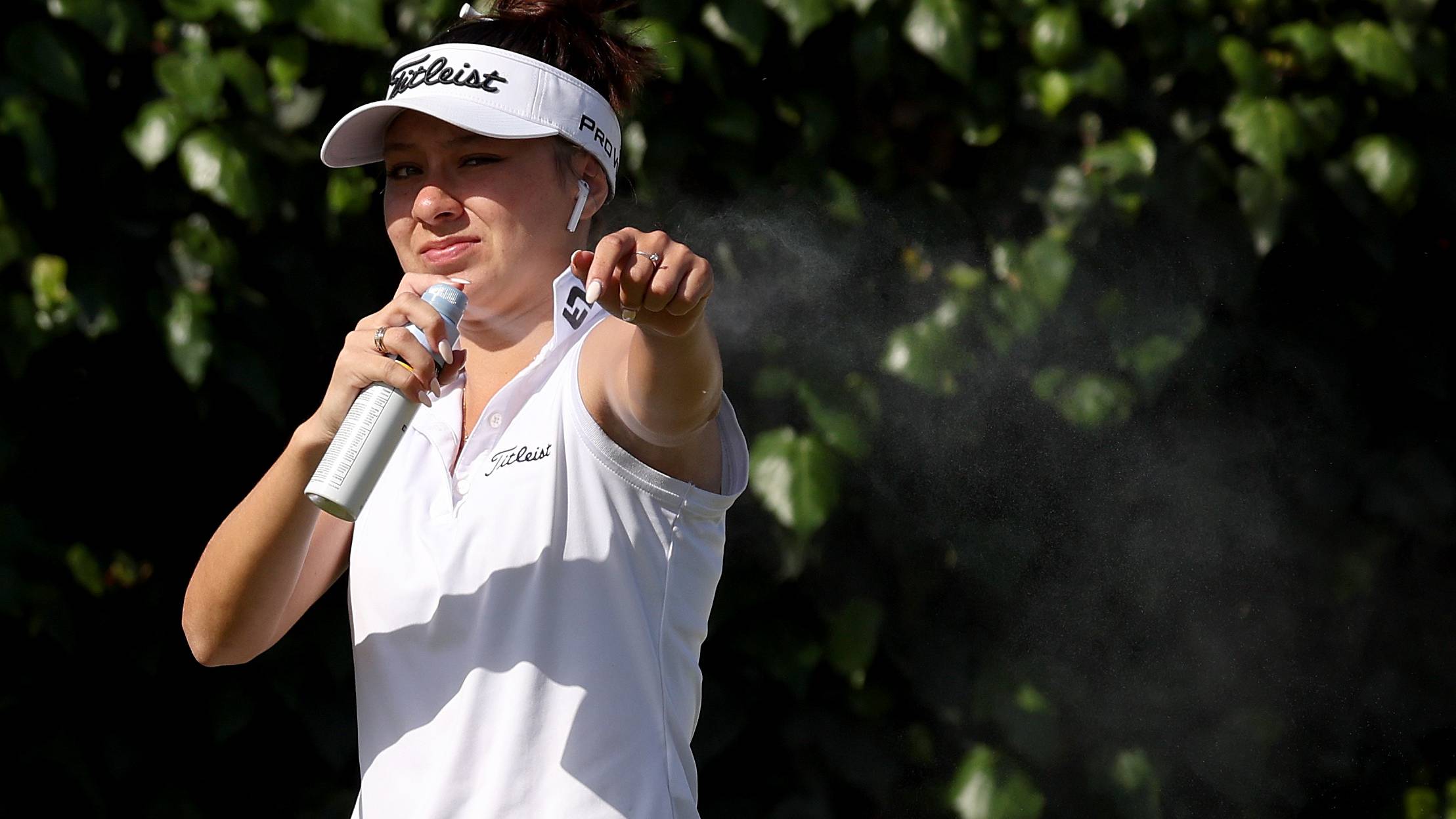 Female golfer spraying herself in the sun