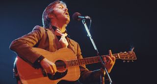 Eric Clapton plays a Martin acoustic onstage in 1974, with his cigarette wedged between the strings