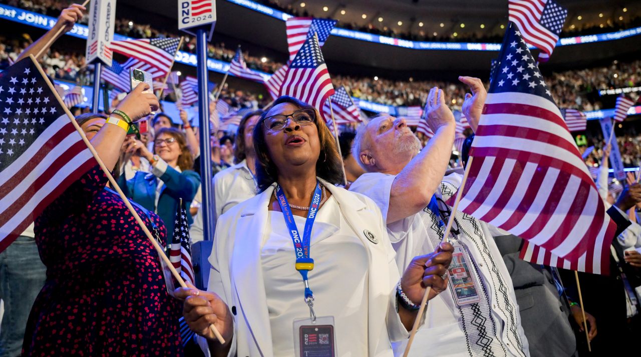 Delegates wearing white wave US flags during the Democratic National Convention (DNC) at the United Center in Chicago, Illinois, US, on Thursday, Aug. 22, 2024. 