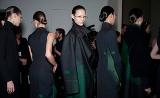 Female models stood in a line wearing black coats