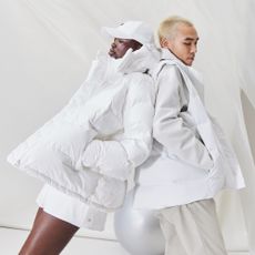 Two models posing in front of a white background wearing A/W 23 lululemon white puffer coats and accessories
