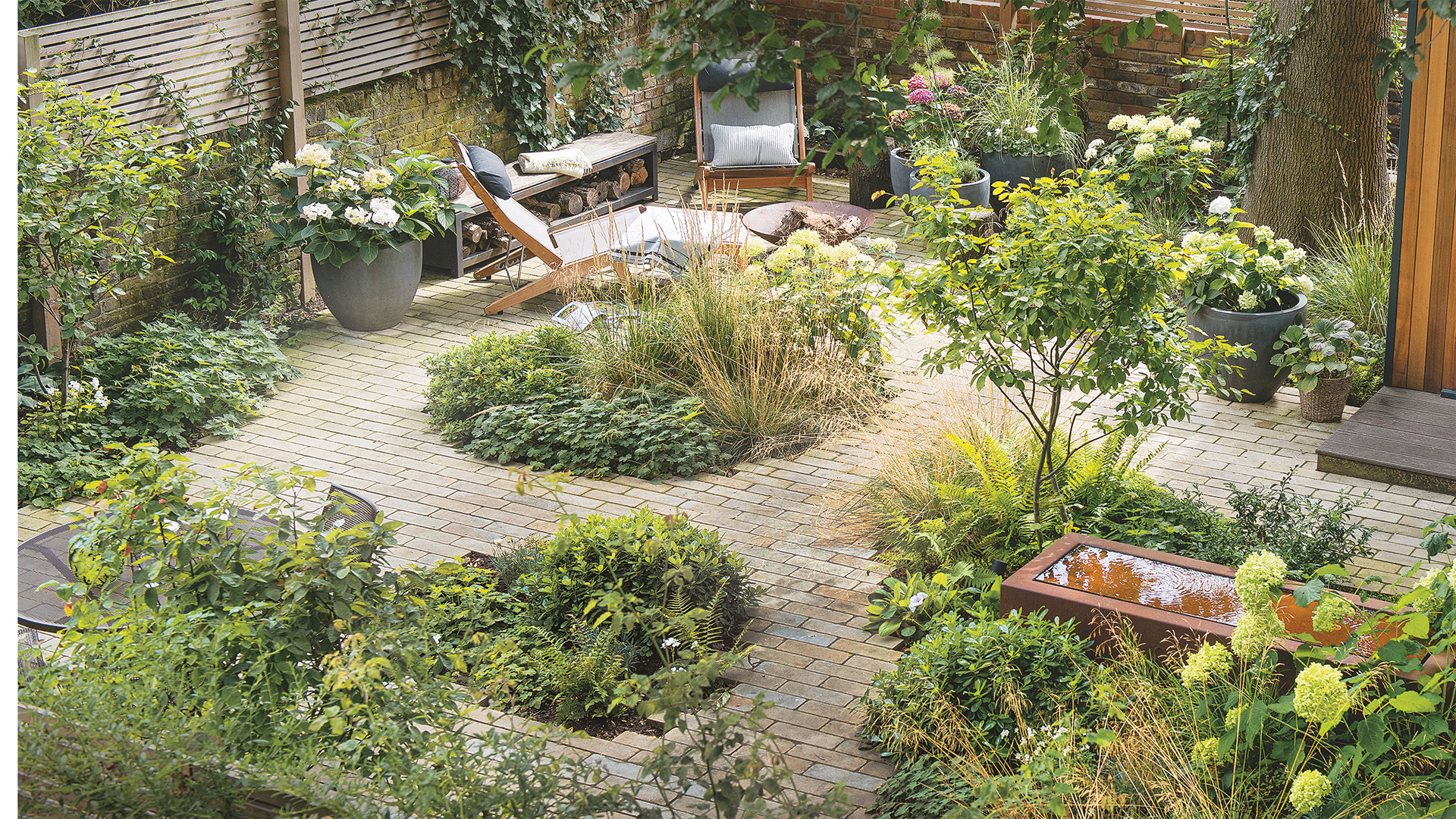 Courtyard garden with evergreen planting, water feature and brick paving
