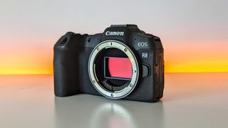 Canon EOS R8 set against a white backdrop with orange glow