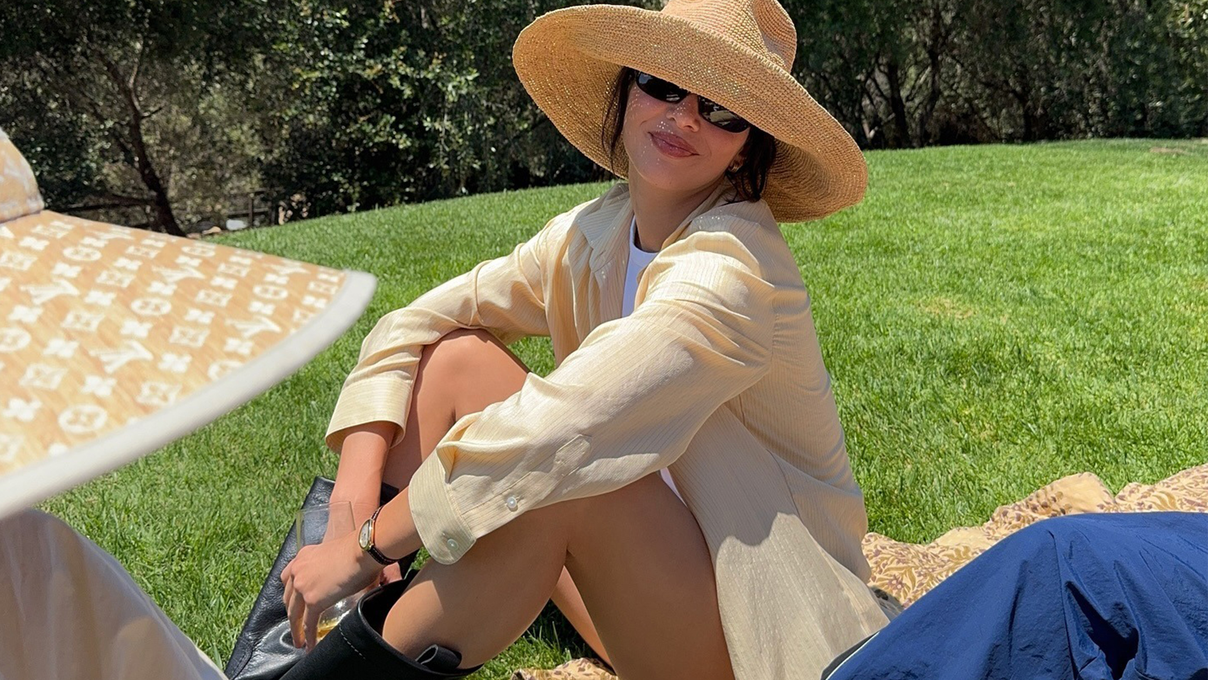 Kendall Jenner wears a straw hat, yellow shirt, and black pull-on boots.