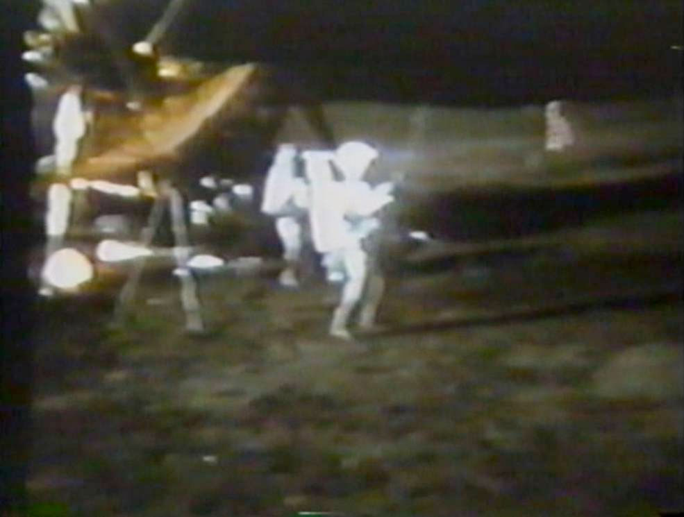 a film still of an astronaut in a white spacesuit swinging a golf club on the moon