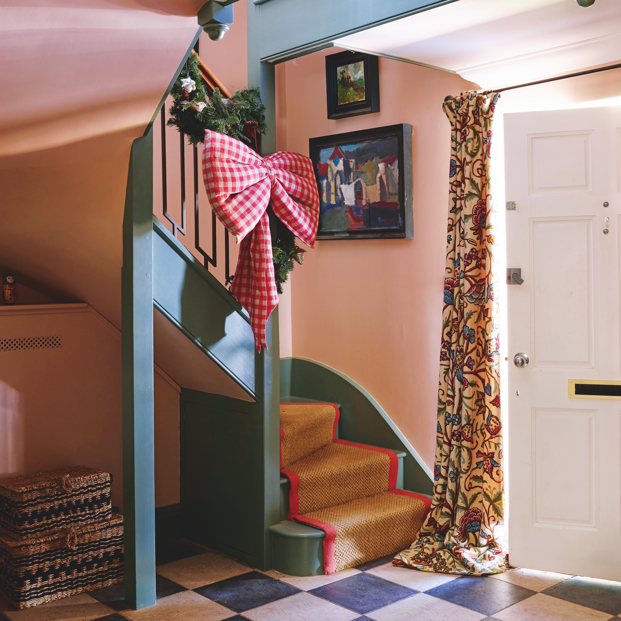 entrance hall of house with black and white check floor tiles and green painted staircase with sisal runner