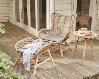 rattan garden chair with matching footstool on a decked terrace